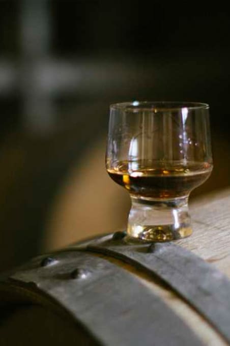 A glass of rum on top of the barrel