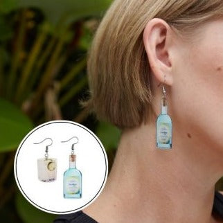 Close-up of woman wearing liquor-inspired acrylic Abrolhos Gin mini earrings with stainless steel hooks.